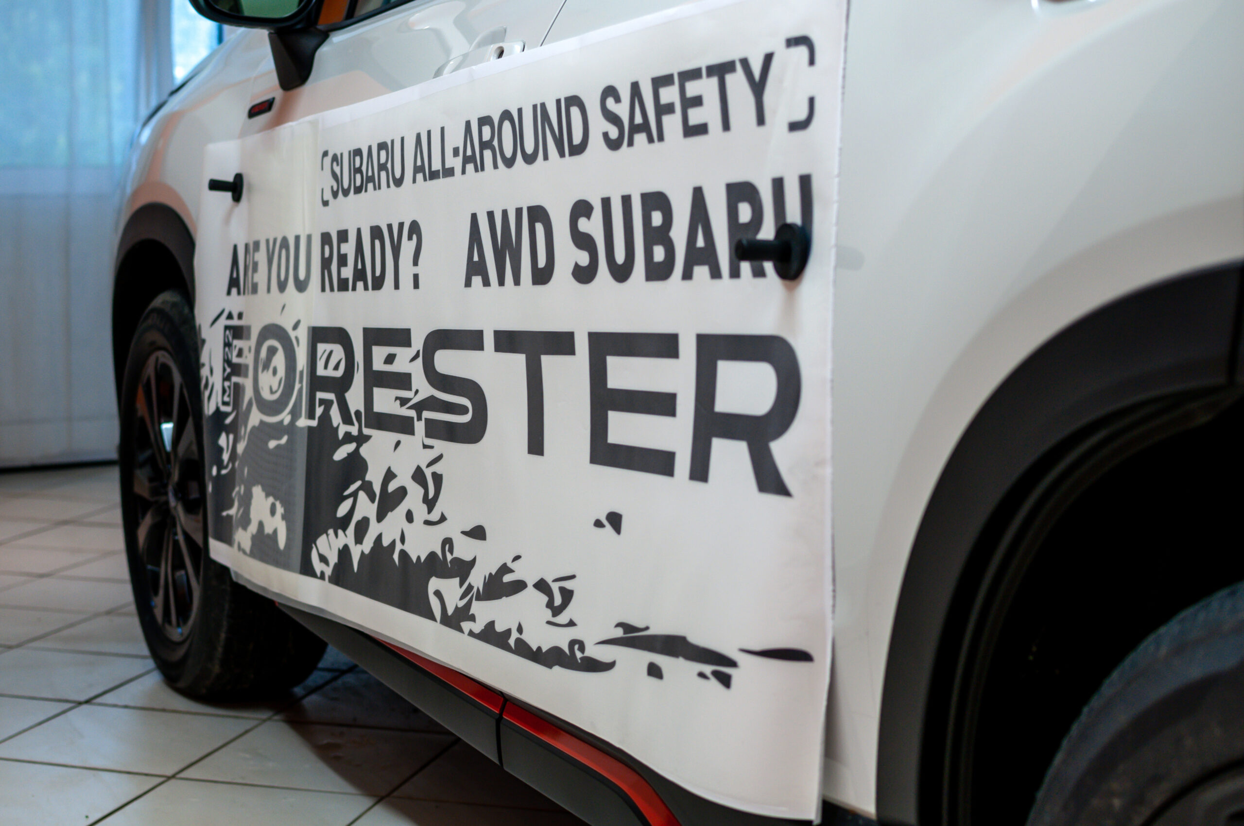 Brno, Czech Republic - 20 April 2023: Installation of foil stickers on the side of a white SUV. Advertising black lettering on paper on the side of the car.